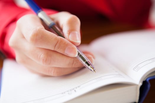 Close-up  of hand holding pen and writing in diary of hand writing in diary