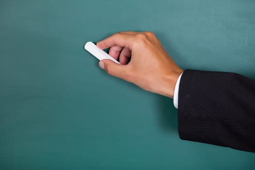 Close-up Of A Hand Writing On Chalkboard