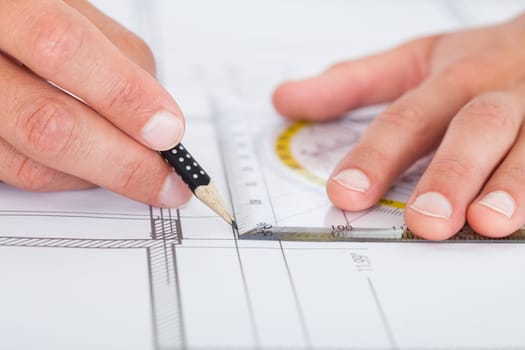Close-up Of Person's Hand Drawing Plan On Blue Print