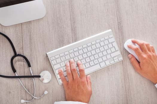 Close-up Of Male Doctor's Hand Typing On Computer Keyboard