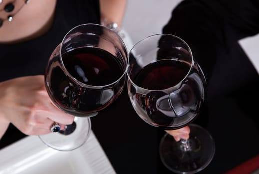 Close-up of couple tossing wine in restaurant