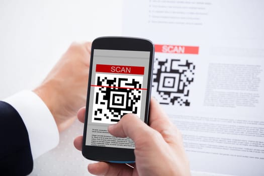 Close-up Of Businessman Scanning A Barcode Using Cell Phone