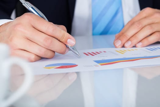 Close-up Of A Businessman Writing On Graph Printed On Paper