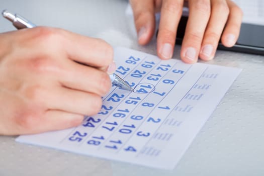Close-up Of Man Highlighting Date On Calendar