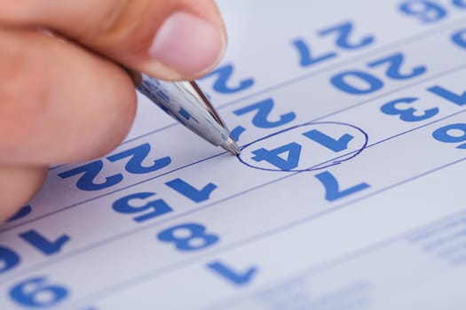 Close-up Of Man Highlighting Date On Calendar