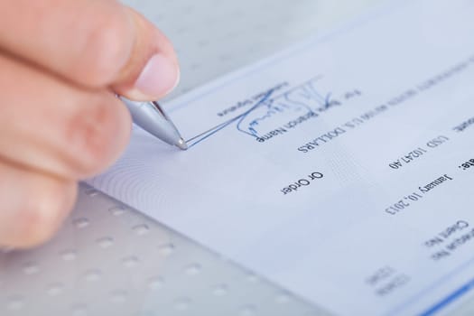 A Male Hand Filling Out The Amount On A Cheque