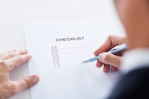Close-up Of Human Hand Filling Check Boxes On Form