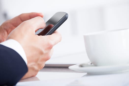 Close-up Of Businessman Using Cell Phone While Having A Break