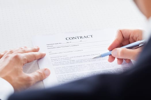 Close-up Of Businessman Holding Pen To Sign On Contract Paper