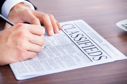 Close-up Of Young Businessman Reading Classifieds On Newspaper