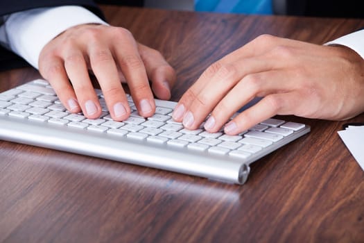 Close-up Of Businessman Typing On Computer Keyboard
