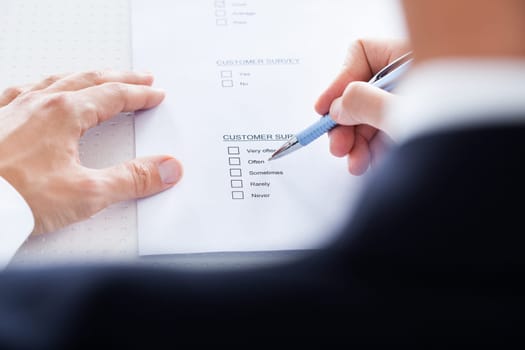 Close-up Of Human Hand Filling Customer Survey Form