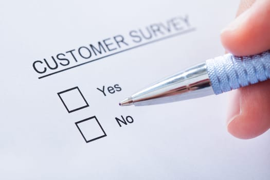 Close-up Of Human Hand Filling Customer Survey Form