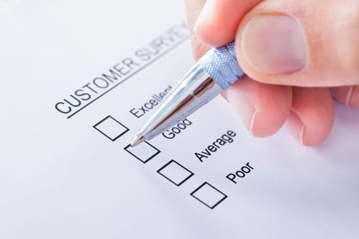 Close-up Of Human Hand Filling Customer Survey Form
