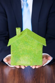 Businessman Sitting In Front Of House Covered With Grass