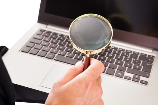 Close-up Of Businessman Looking At Laptop Through Magnifying Glass