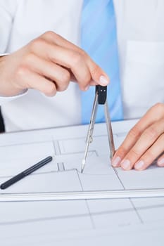 Close-up Of Male Architect Working On Blueprint At Desk