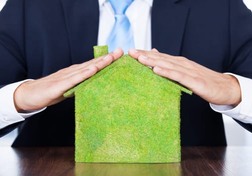 Businessman Sitting In Front Of House Covered With Grass