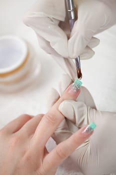 Beautician applying gel on fingernails. Close-up shot