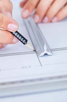 Close-up Of Male Architect Working On Blueprint At Desk
