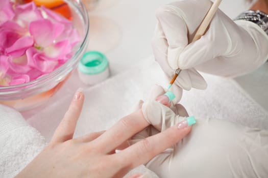 Beautician painting fingernail tips in green. Close-up shot