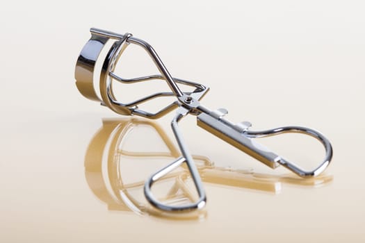 Close-up Of Eyelash Curler Over Reflective Background