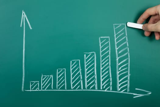 Hand drawing growth chart on green chalkboard