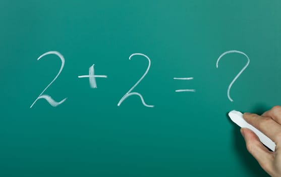 Hand writing 2 plus 2 on blackboard
