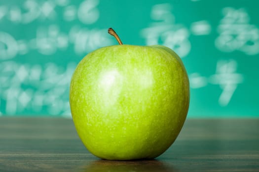 Photo of green apple on the school desk