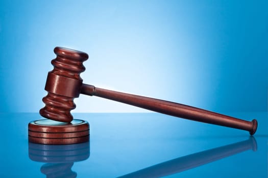 Wooden Gavel Resting On Block Over Blue Background