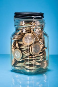 A Jar Full With Euro Coins Over Blue Background