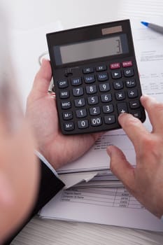 Close-up Of Mature Businessman Calculating Finance At Office