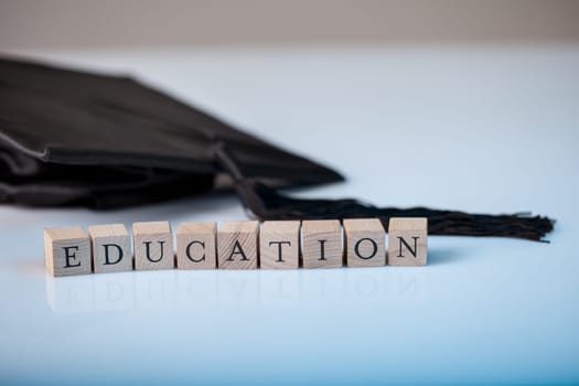 Education concept with the alphabet letters for Education spelt out on wooden blocks beside a graduation cap