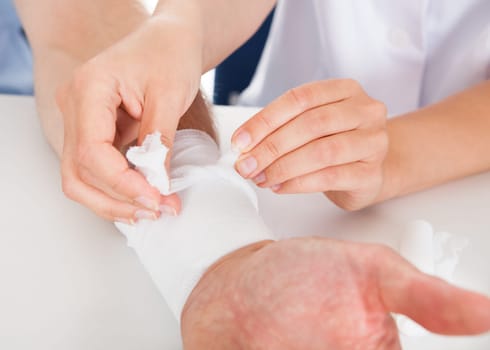 Close-up Of Female Doctor Bandaging Patient's Wrist
