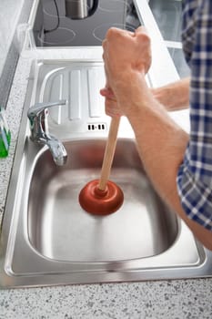 Closeup Of Man Using Plunger In Kitchen Sink