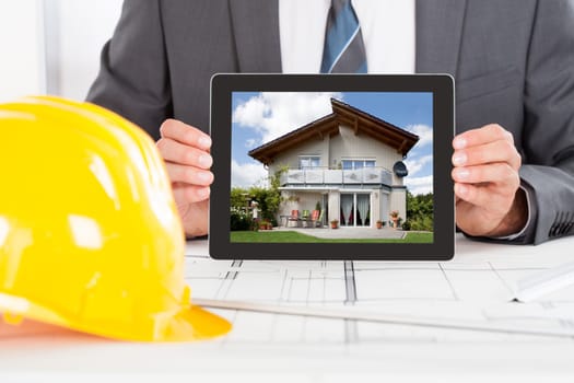 Close-up Of Male Architect Holding Digital Tablet In Front Of Hardhat