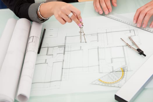 Cropped overhead view of a male and female architect discussing a set of blueprints spread out on a table