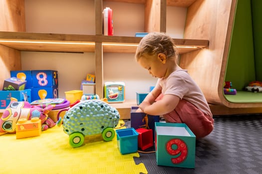 Toddler having fun with building blocks and toys in a cheerful and engaging playroom