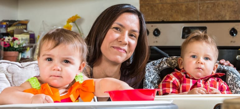 A mother in the kitchen poses with babies