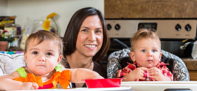 A mother in the kitchen poses with babies