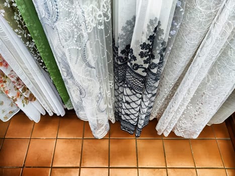 Lots of curtains or fabrics and the floor under them. Sale of curtains and fabrics in the store. Background, texture, place for text, copy space and frame