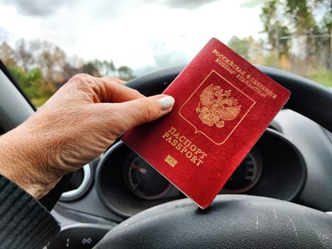Russian passport in hand of driver woman. Russian cars banned for entering in Europe. Russian tourism closed during war of Russia and Uk. Confiscation of Russian car and sanctions against Russians