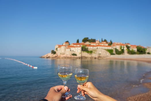 Sveti Stefan Island, Montenegro July 5, 2021: Adriatic Sea. Glasses with wine on the background of the island. Romantic trip