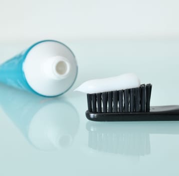 Toothbrush and toothpaste on light blue background