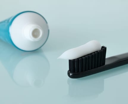 Toothbrush and toothpaste on light blue background