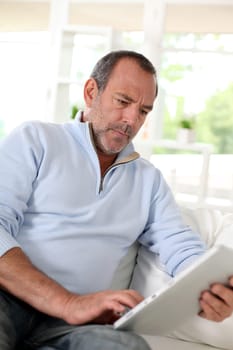 Senior man at home using electronic tablet