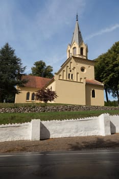 Yellow church behind white cemetery wall