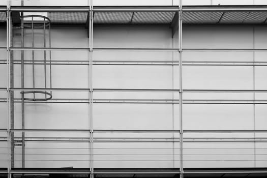 The photograph of a sheet metal wall on a public building with a walk-in scaffolding and a fire ladder.