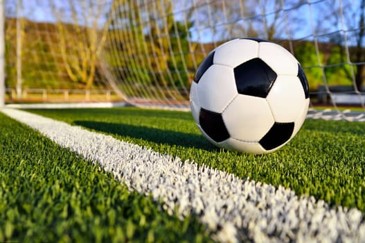 Football lies on a sunny football pitch behind the goal line