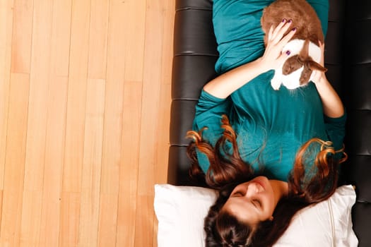 A young hispanic girl with a rabbit on the sofa. .